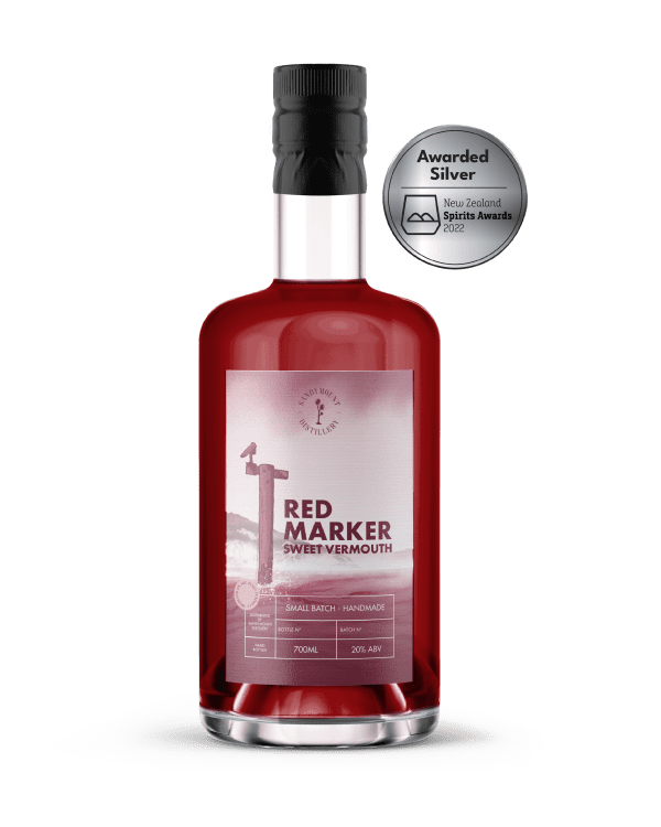 A clear glass bottle with deep red/ purple liquid (sweet vermouth). On it is a faded red label with a ship marker from the harbour, titled Red Marker.