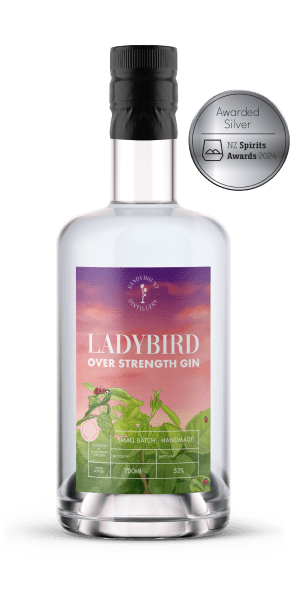 A glass bottle of Sandymount's Ladybird Navy Strength Gin with a vibrant pink and green label. A silver medal is to the right of the bottle.